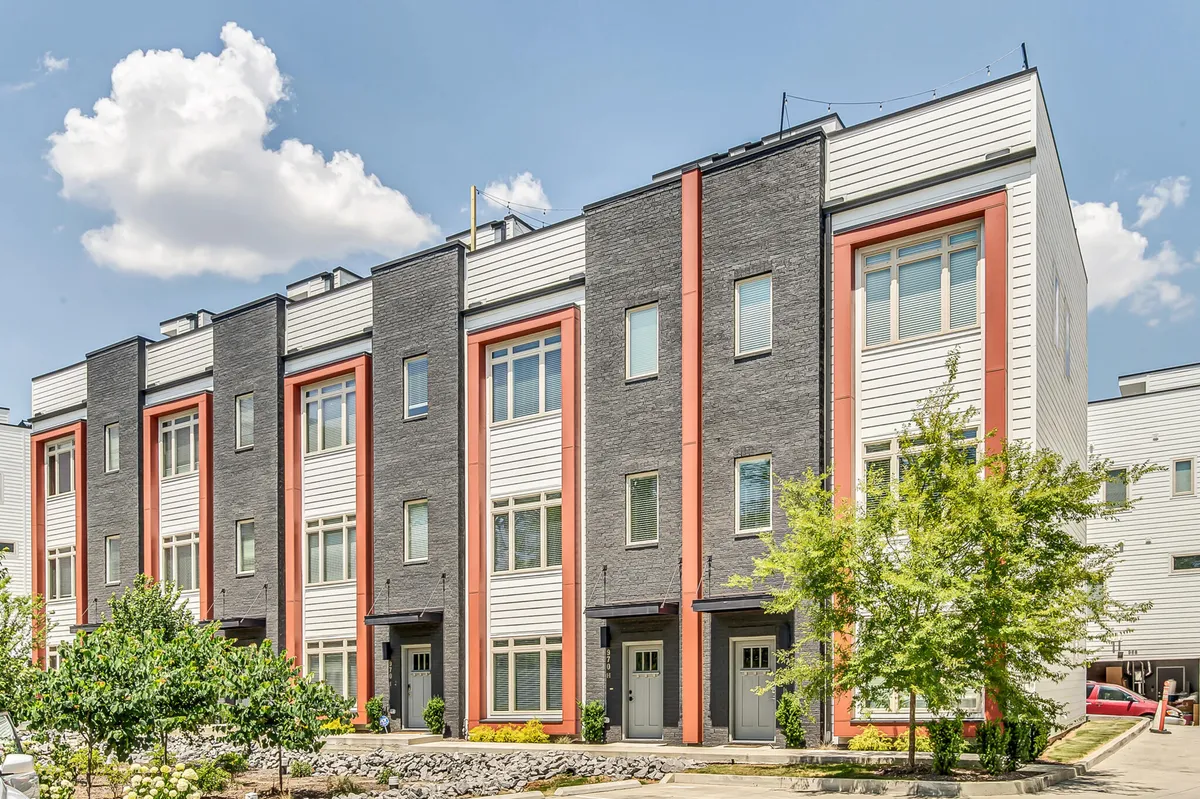This image features rows of modern townhouses with landscaped common areas under a clear blue sky, evoking a sense of vibrant community life. The setting is ideal for outdoor family activities, summer barbecues, and neighborhood gatherings, reinforcing the home's suitability for large groups.