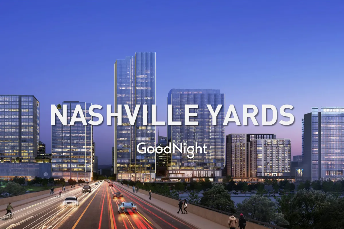 This image features tall glass buildings in downtown Nashville, a busy road filled with activity, an illuminated skyline, and prominent Nashville Yards signage. The scene is vibrant and energetic, capturing the essence of Nashville's business district and its urban energy.