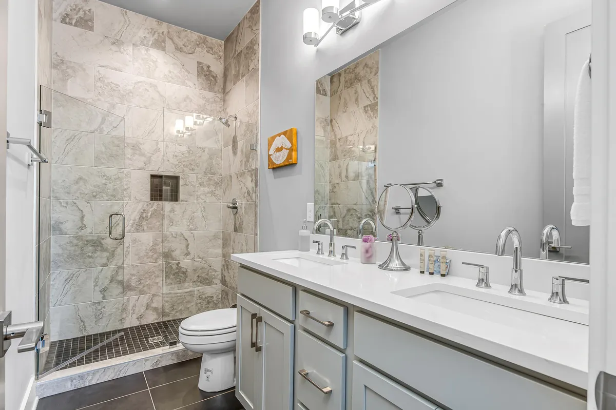 A modern en-suite bathroom with a double vanity, walk-in shower, framed mirror, and tasteful artwork. The space feels refreshing and spa-like, perfect for morning routines or winding down after a city adventure.